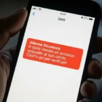 Mano che tiene uno smartphone su cui è visibile un finto messaggio di allarme bancario