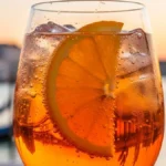 un calice da vino colmo di Spritz color arancio brillante