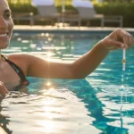 una persona sorridente a bordo piscina mentre immerge una striscetta reattiva in un'acqua blu e cristallina