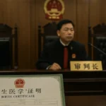 Aula di tribunale cinese con giudice che tiene in mano un certificato di nascita