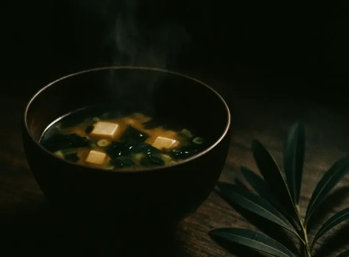 Ciotola di zuppa di miso su un tavolo con foglie verdi accanto