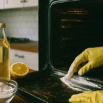 Donna che pulisce interno di un forno incrostato usando una pasta naturale di bicarbonato e una spugna