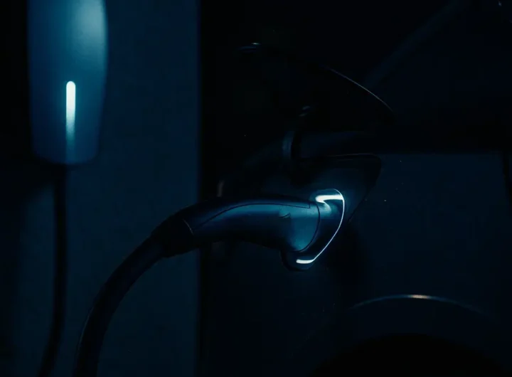 Uomo che ricarica un'auto Tesla di notte a casa con uno sfondo sfocato